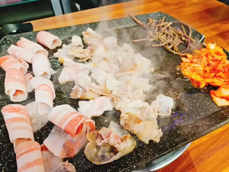 불판 위에서 익어가는 대패삼겹살과 김치