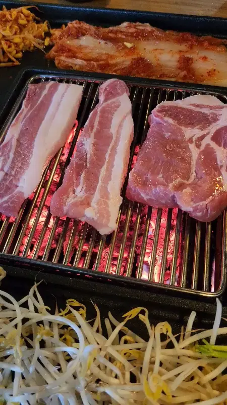 불판 위에서 익어가는 삼겹살과 김치