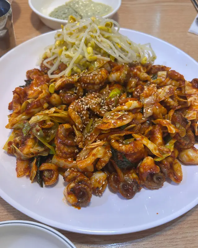 매콤한 쭈꾸미 볶음과 신선한 콩나물이 조화롭게 담겨, 입맛을 돋우는 비주얼을 자랑한다.