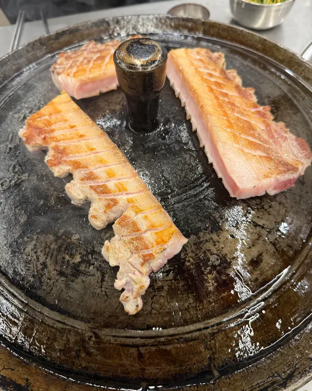 두툼한 삼겹살이 솥뚜껑 위에서 익어가는 모습