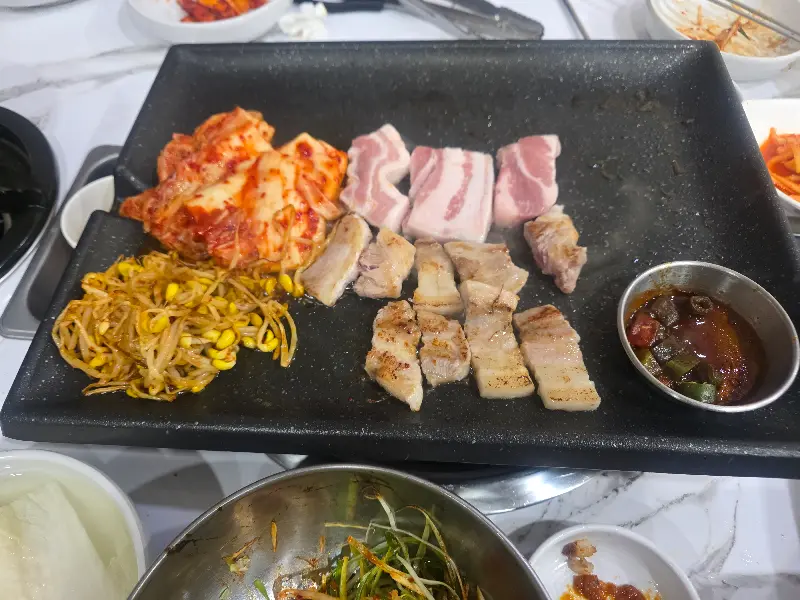 불판 위의 삼겹살과 김치, 콩나물