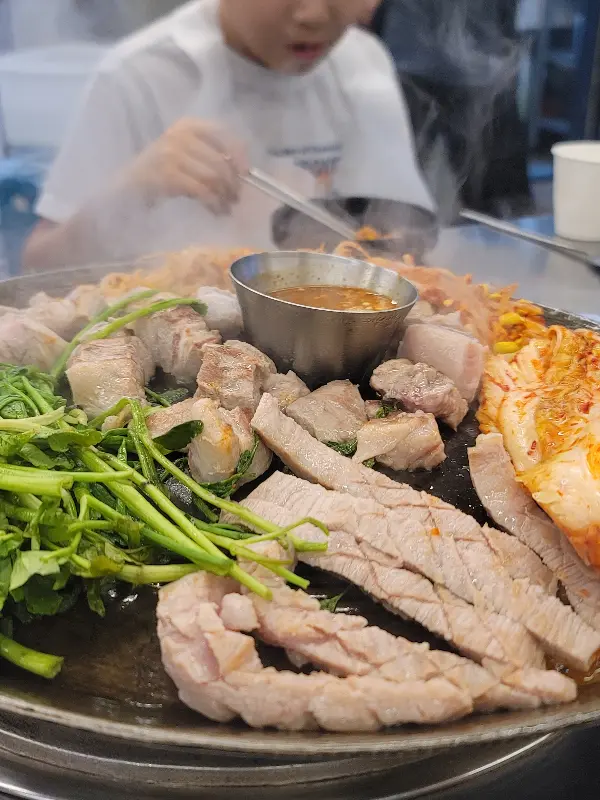 김치, 콩나물, 미나리와 함께 구워지고 있는 삼겹살