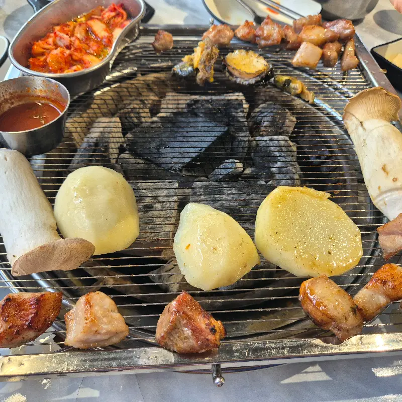 숯불 위에서 맛있게 익어가는 고기, 김치, 버섯, 감자