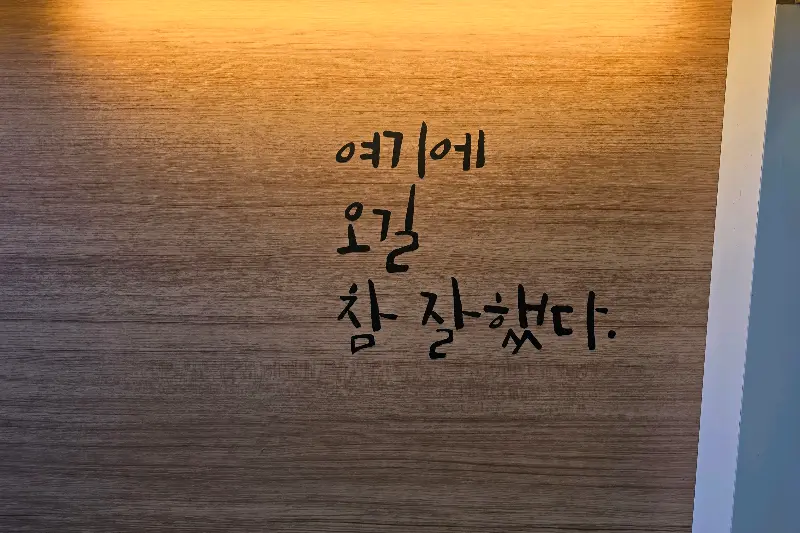 벽에 쓰여진 '여기에 오길 참 잘했다' 문구