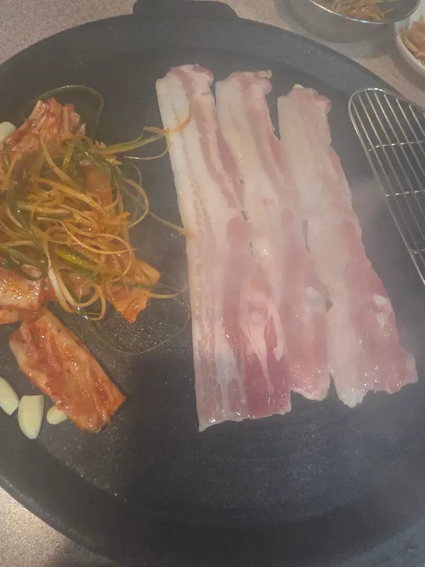 무쇠 솥에 구워지는 삼겹살과 김치, 파절이