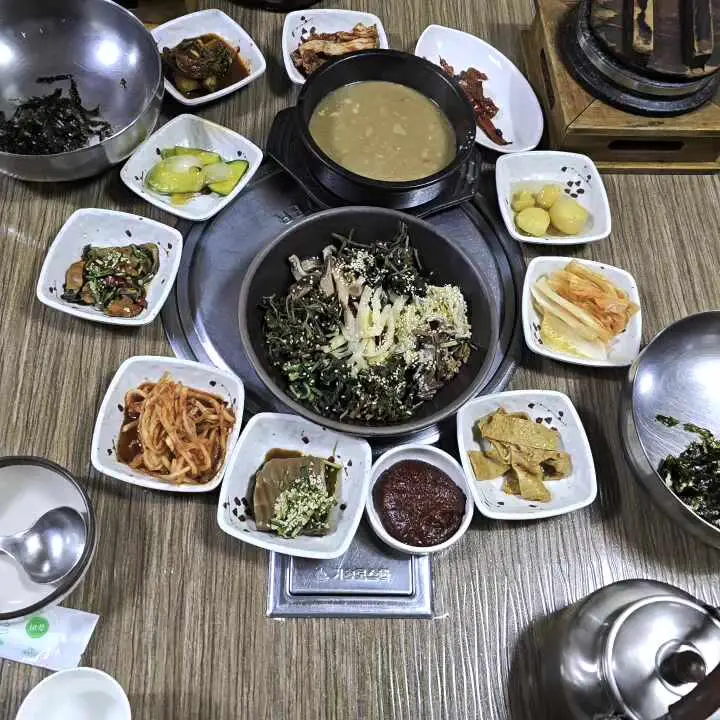 산채비빔밥과 다양한 반찬들이 놓인 푸짐한 테이블 전경