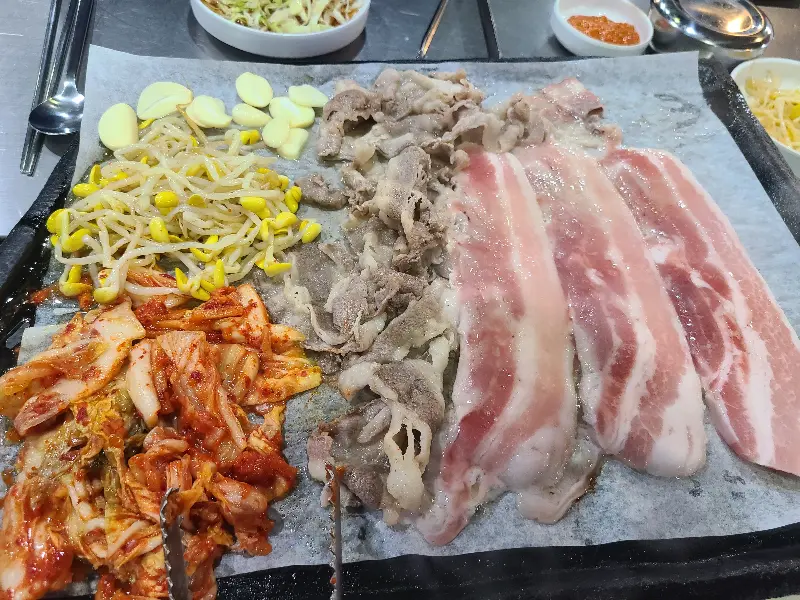 삼겹살과 김치, 콩나물이 푸짐하게 올려진 불판