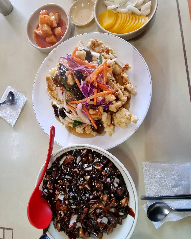 짜장면, 탕수육, 단무지, 양파가 놓인 테이블 전경