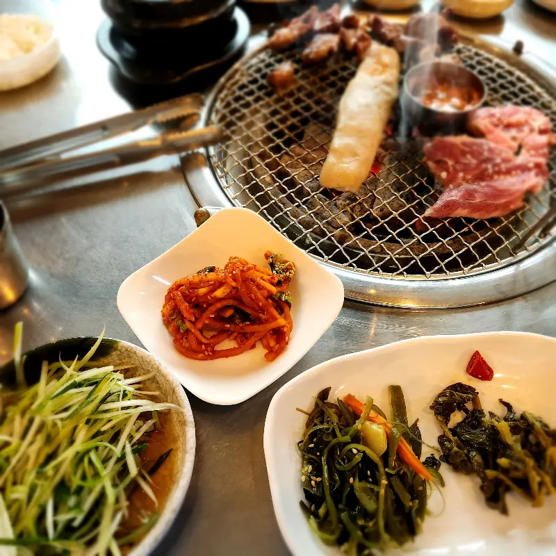 다양한 밑반찬과 구워지고 있는 고기의 모습