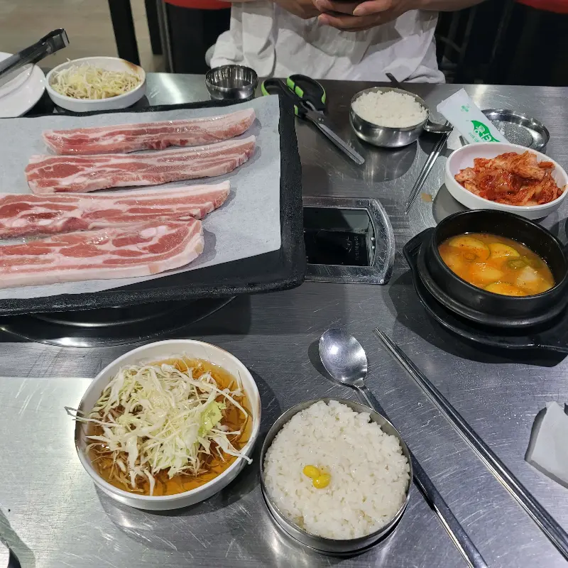 잘 구워진 삼겹살과 푸짐한 밑반찬이 차려진 테이블