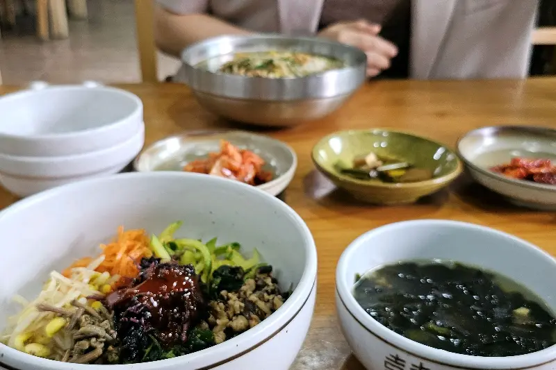 비빔밥과 물국수, 밑반찬이 함께 놓인 테이블