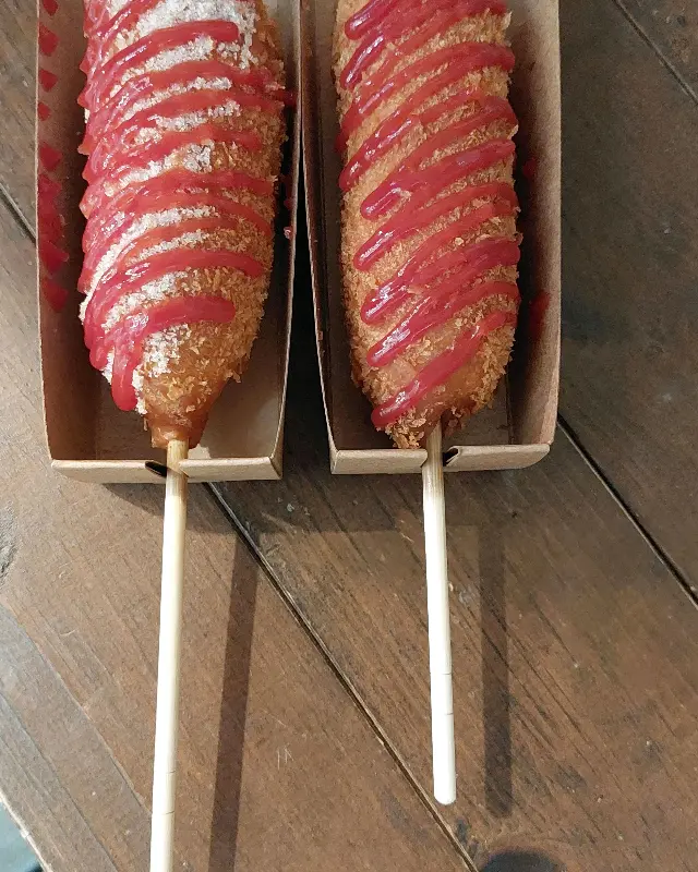 갓 튀겨져 설탕과 케첩이 뿌려진 핫도그