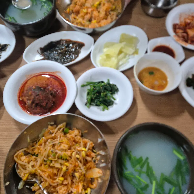 재첩국과 함께 다양한 종류의 밑반찬이 놓여있는 식탁