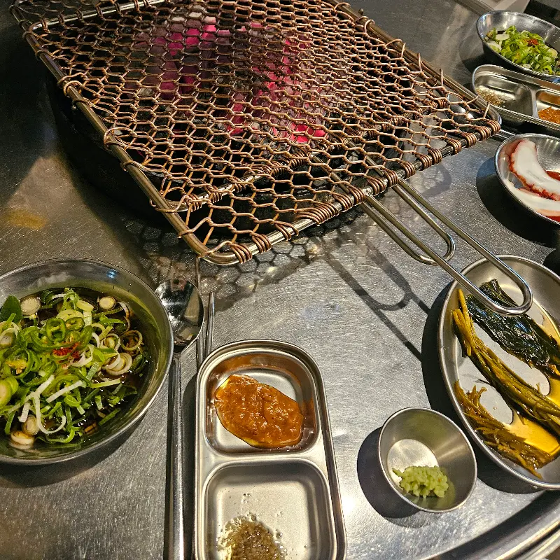 숯불과 밑반찬이 세팅된 테이블 전경