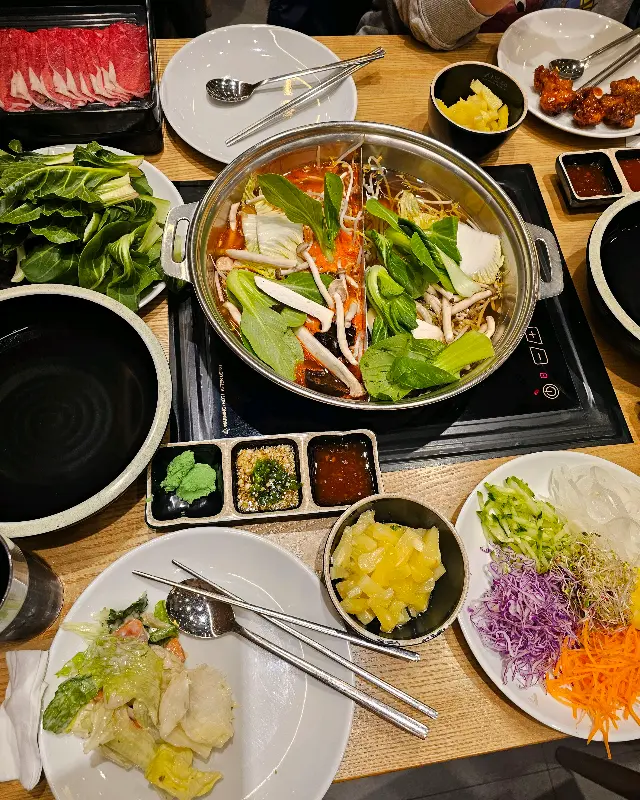 샤브샤브 재료와 샐러드바 음식이 차려진 테이블