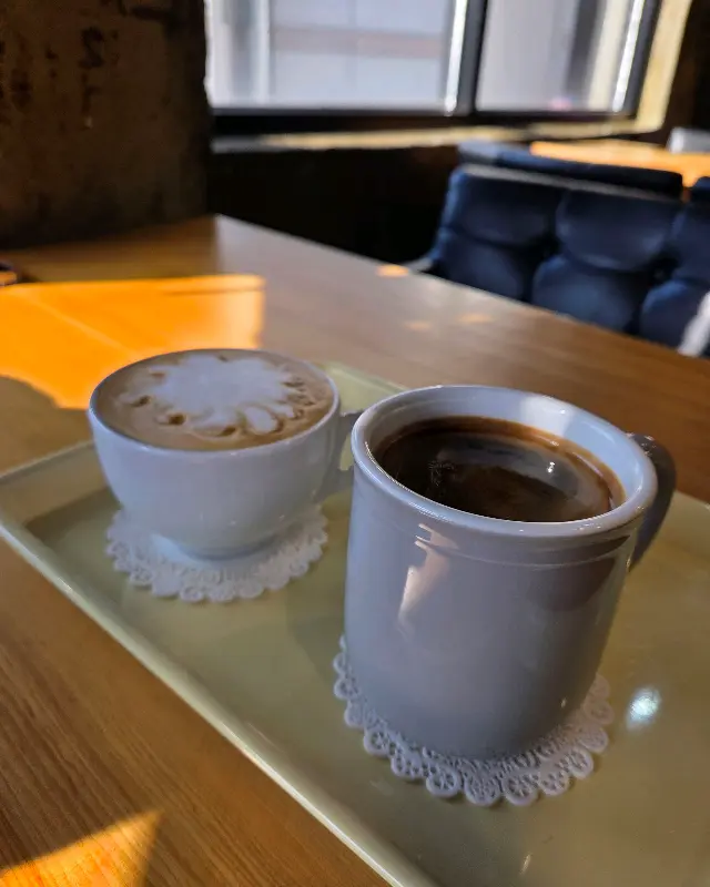 레이스 코스터가 깔린 쟁반 위에 놓인 따뜻한 라떼와 아메리카노