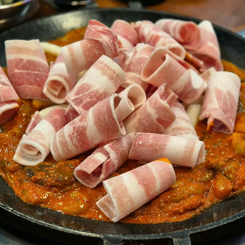 쭈꾸미 볶음 위에 삼겹살을 얹은 모습