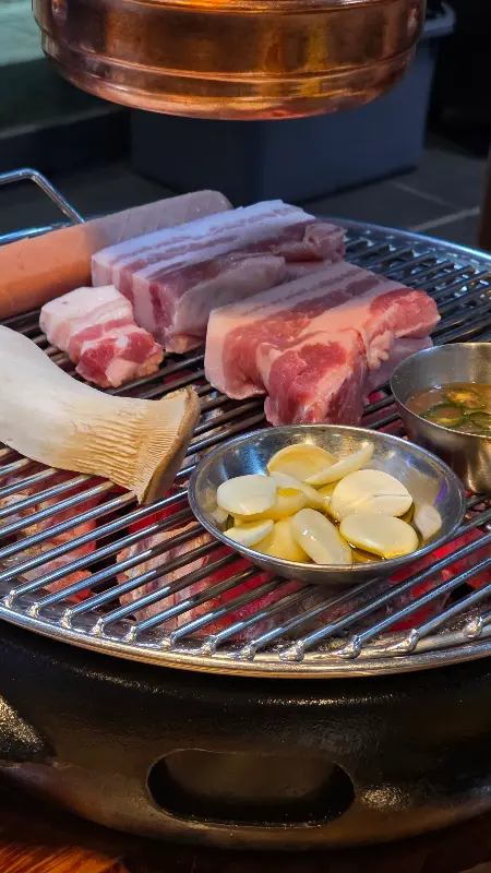 숯불 위에서 익어가는 오겹살과 버섯, 마늘