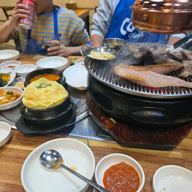 흑돼지, 계란찜, 김치찌개로 가득 찬 테이블