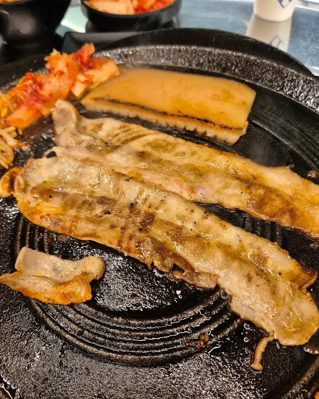 초벌된 삼겹살이 불판 위에서 맛있게 익어가는 모습