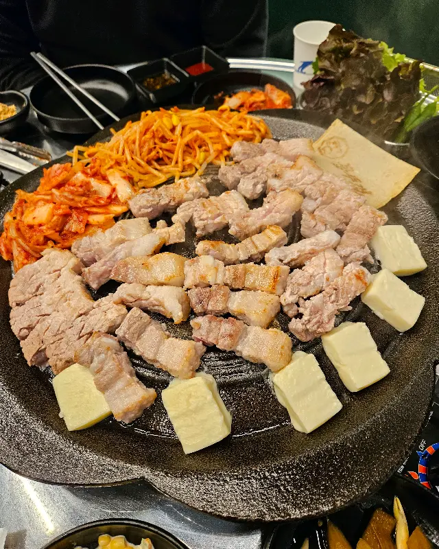 불판 위에 김치, 콩나물, 삼겹살을 함께 구워 먹는 모습