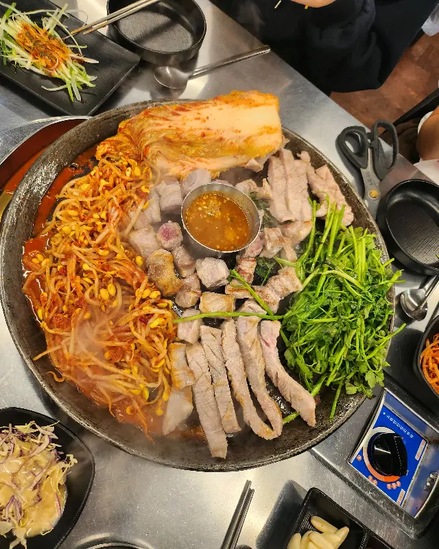 솥뚜껑 위에 푸짐하게 차려진 삼겹살 한 상