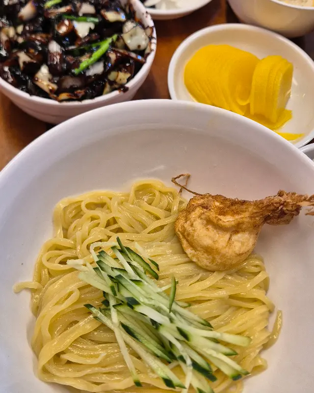 간짜장, 짜장 소스, 단무지, 양파가 테이블 위에 놓여 있는 모습