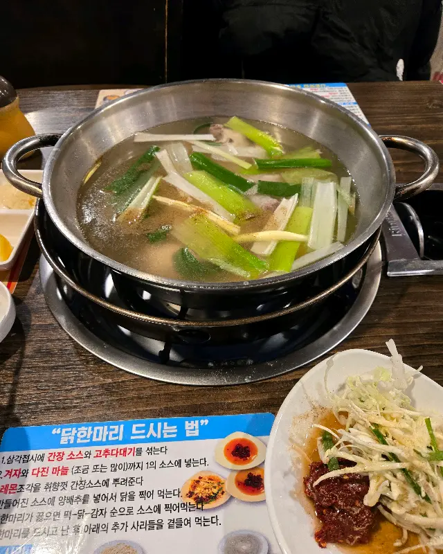 뽀얀 육수와 닭, 대파가 담긴 닭한마리 냄비