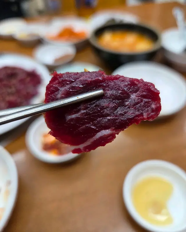 젓가락으로 집어올린 생고기 한 점