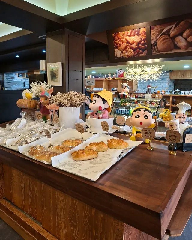 다양한 빵들이 진열되어 있는 모습. 짱구 캐릭터 인형들이 곳곳에 놓여 있어 아기자기한 분위기를 더한다.