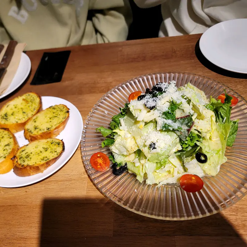 싱싱한 채소와 드레싱이 조화로운 샐러드와 갓 구워져 따뜻한 마늘빵