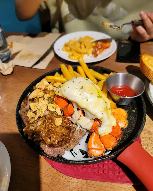 스테이크와 랍스터, 감자튀김이 함께 제공되는 푸짐한 메뉴 구성