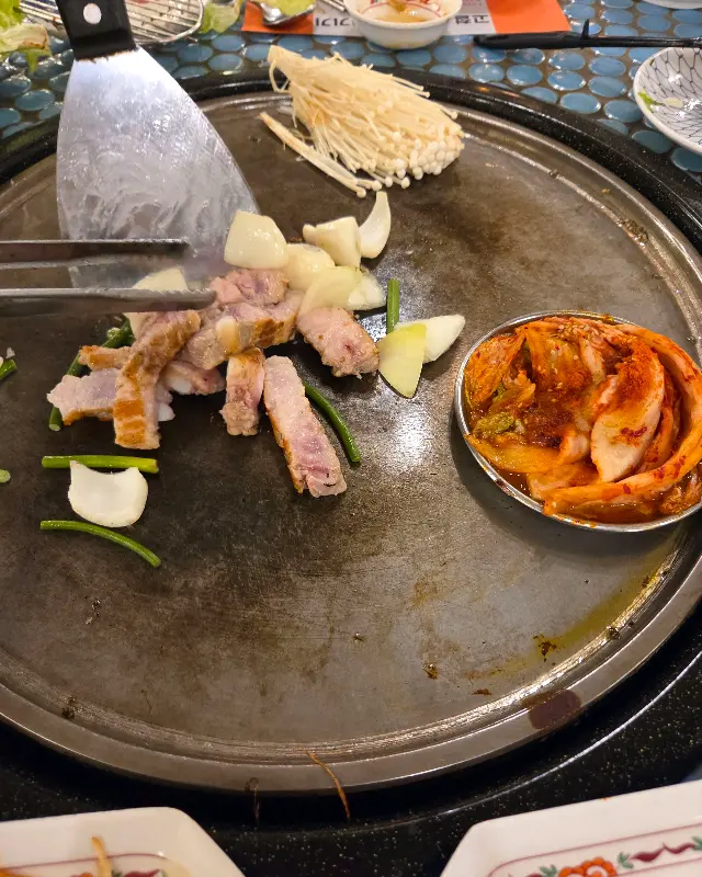 철판 위에 구워지는 삼겹살, 김치, 버섯