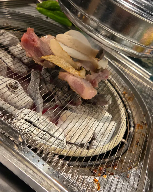 숯불 위에서 노릇하게 익어가는 삼겹살과 버섯