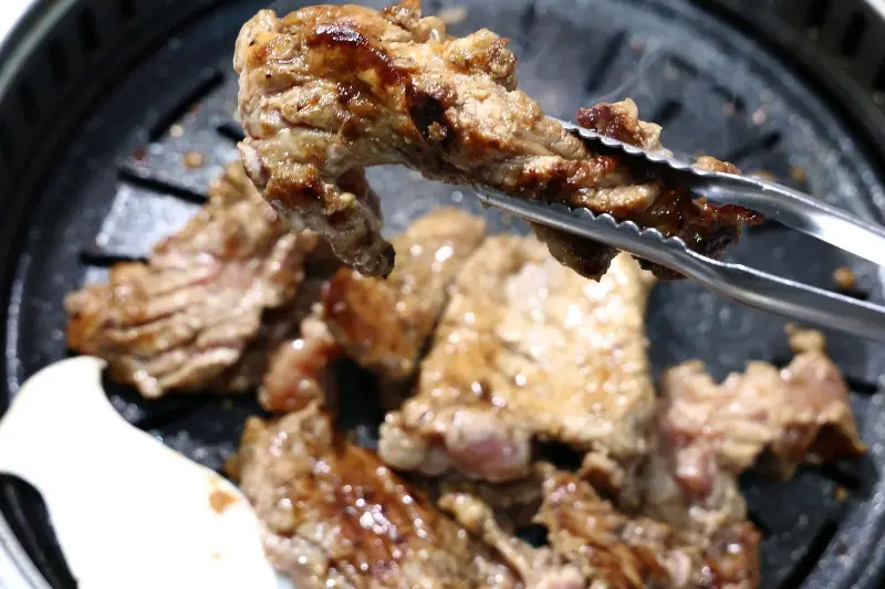 윤기가 흐르는 돼지갈비 한 점을 들어 올린 모습