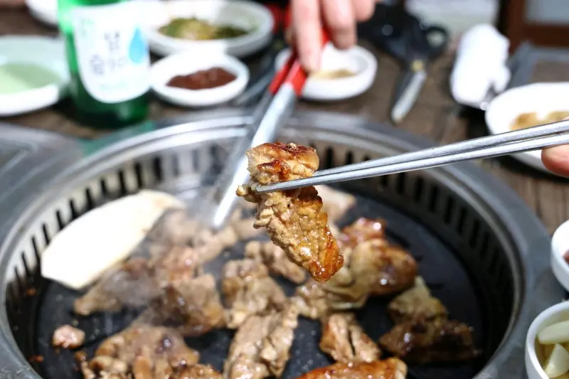 잘 구워진 갈비 한 점을 젓가락으로 집어 올린 모습