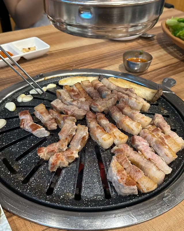 두툼한 삼겹살이 불판 위에서 맛있게 익어가는 모습