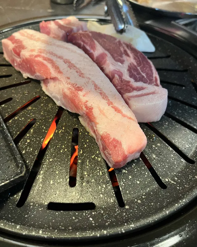 두툼한 삼겹살이 불판 위에서 익어가는 모습