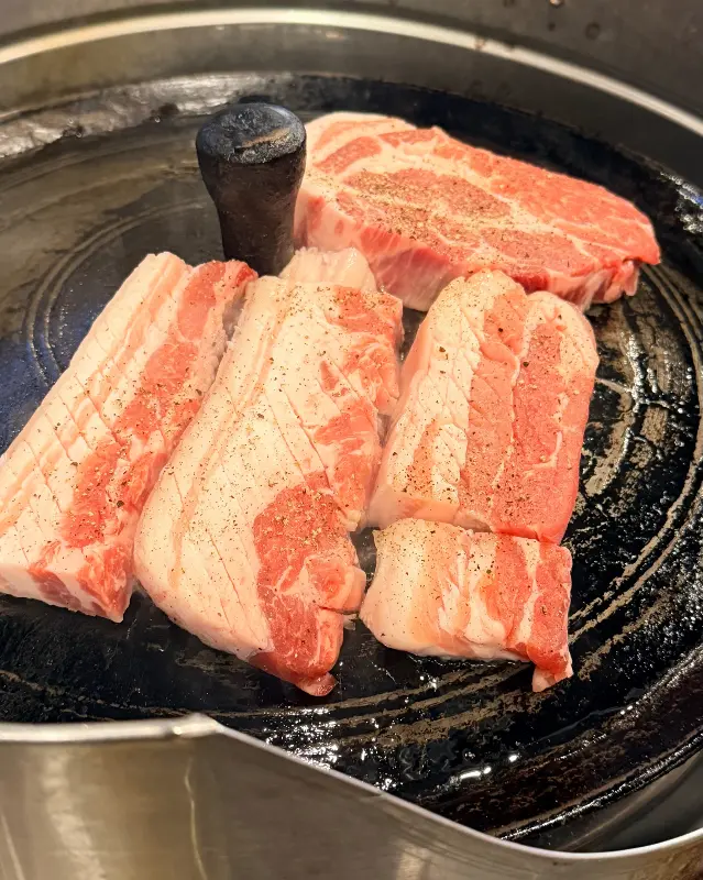 솥뚜껑 위에 올려진 삼겹살과 목살