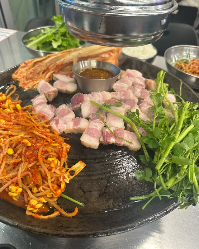 삼겹살과 함께 구워지고 있는 김치, 콩나물, 미나리