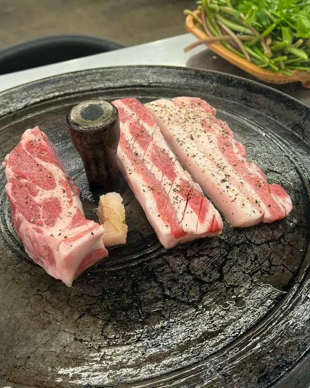 솥뚜껑 위에 올려진 삼겹살의 모습