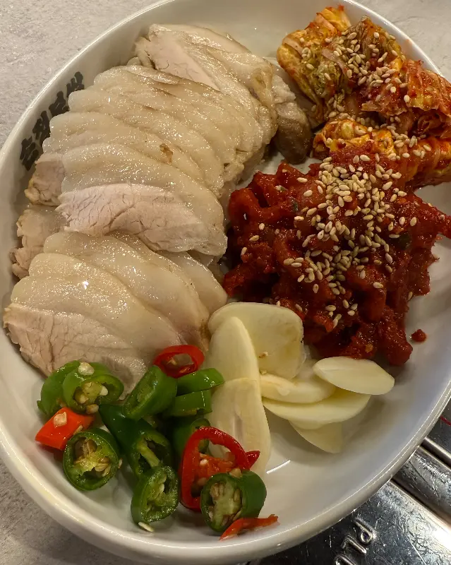 윤기가 흐르는 가브리살 보쌈과 매콤한 김치 속이 담긴 접시