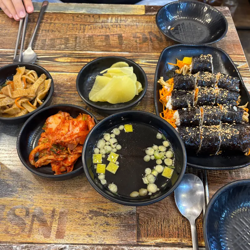 김치, 단무지, 어묵볶음, 꼬마김밥 등이 담긴 반찬 그릇들