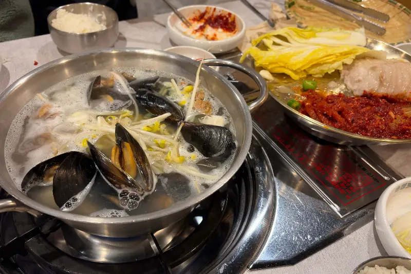 해물이 듬뿍 들어간 칼국수가 테이블 위에서 보글보글 끓고 있는 모습