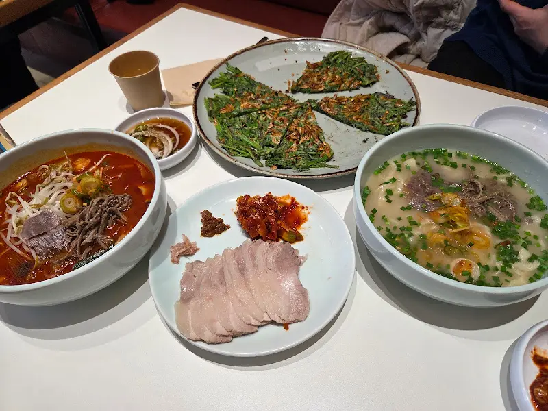 칼국수, 미나리전, 수육이 놓인 테이블 전경