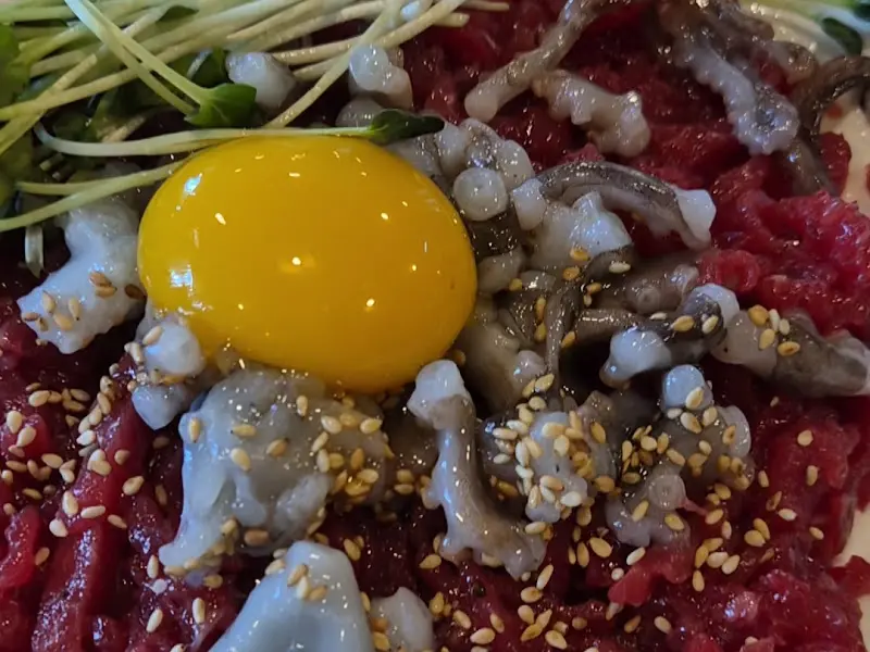 육회탕탕이의 클로즈업 샷, 노른자와 참깨가 뿌려진 모습