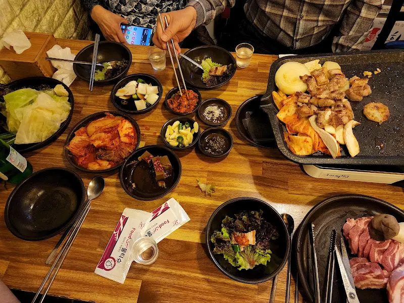 다 익은 삼겹살과 김치, 버섯, 감자가 불판 위에 놓여 있는 모습