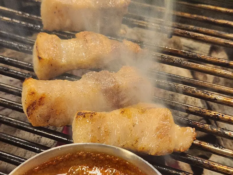 초벌된 큼지막한 고기가 숯불 위에서 지글거리는 모습