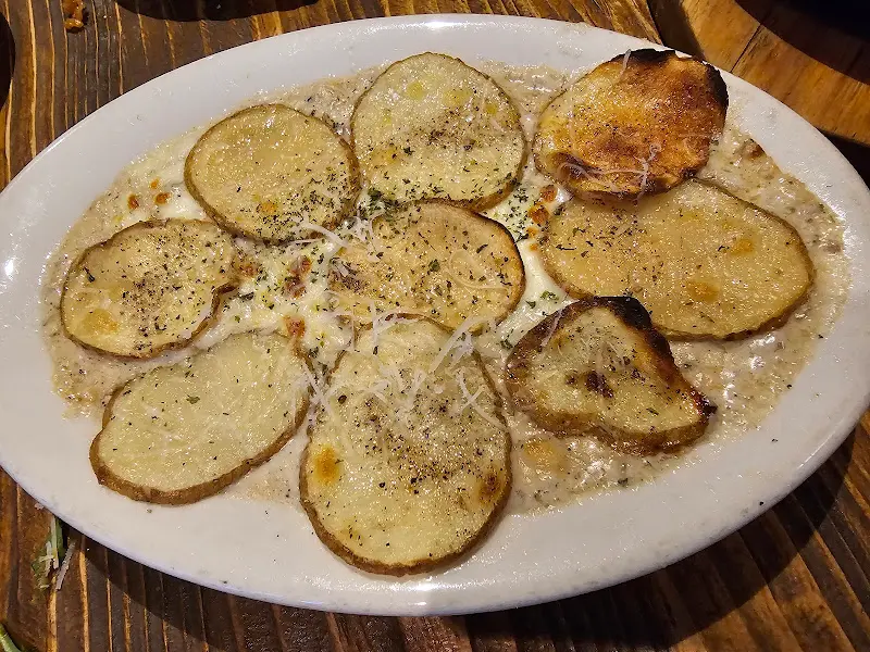 따뜻한 크림 소스에 감싸인 채 슬라이스된 감자들이 겹겹이 쌓여있는 그라탕의 모습