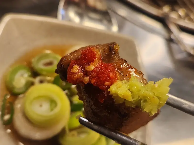 잘 구워진 고기에 와사비와 쌈장을 올려 먹는 모습